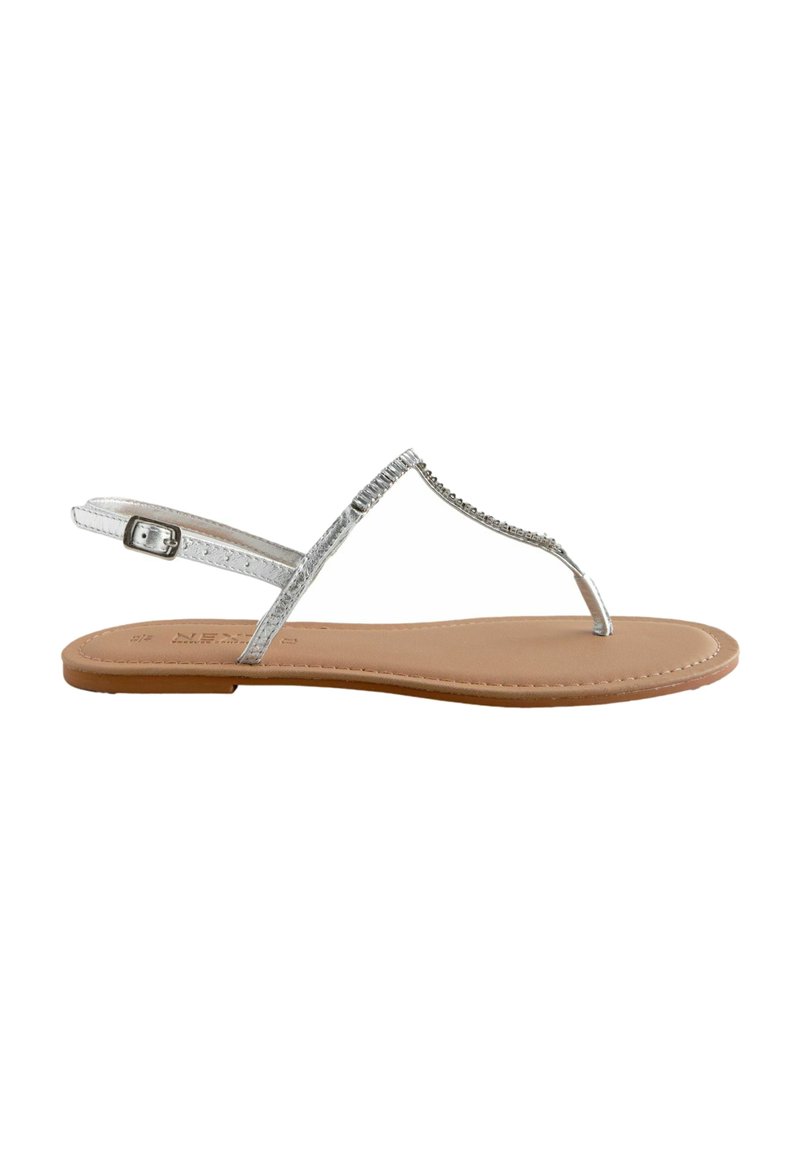 Sandalias de dedo metálicas plateadas con una correa estrecha, hebilla ajustable en el tobillo y suela sintética color bronceado. Diseño plano con un detalle mínimo.
