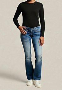 Czarna bluzka z długim rękawem zestawiona z niebieskimi jeansami o wyrazistym, wyblakłym kolorze i rozszerzanych nogawkach, uzupełniona białymi tenisówkami.