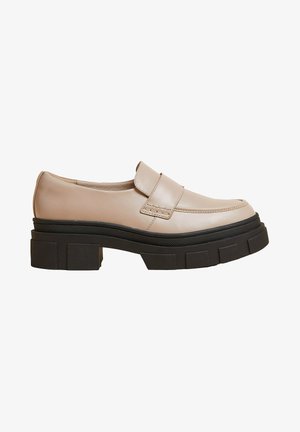 Mocassins en cuir beige avec un bout rond et une sangle latérale, dotés d'une semelle en caoutchouc noir épaisse avec des accents surélevés pour une meilleure adhérence.