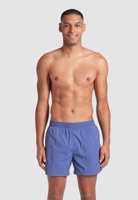 Pantaloni da nuoto leggeri e blu, con vita elastica e tasche laterali, caratterizzati da un design semplice e una texture liscia.
