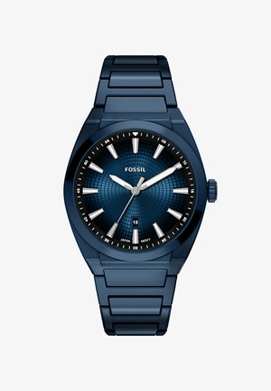 Blue stainless steel Fossil wristwatch with textured dial, silver hour markers, three hands, and date display at six o'clock position.
