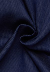 Marineblauwe, gestructureerde stof met een gladde oppervlakte en fijne, geweven patronen, gedrapeerd om zachte plooien en kreukels te onthullen.