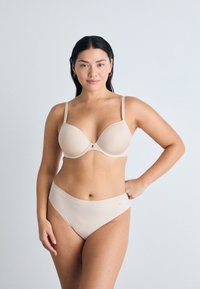 Naakt beha en hooggesneden slip set gemaakt van gladde stof. De beha heeft verstelbare banden en een subtiele gouden accent. Naadloos ontwerp.