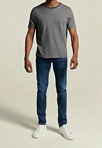 Grå kortärmad t-shirt kombinerad med blå denimjeans och vita sneakers. T-shirten har rund hals och jeansen är slim fit.
