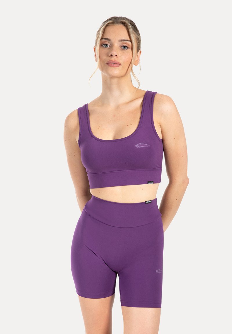 Lila atletisk crop top med rund halsringning och matchande höga shorts. Slät tyg med minimal märkning och en figursydd design.