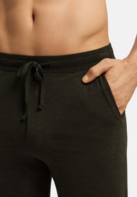 Donkergroene joggingbroek gemaakt van zachte stof, met een trekkoord in de taille, zijzakken en een gladde textuur.