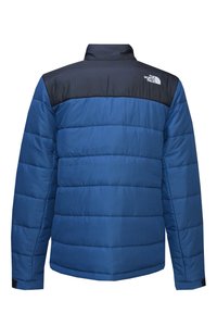 Giacca a palloncino blu con yoke blu scuro, design trapuntato, colletto alto e logo sulla spalla sinistra. Presenta maniche lunghe e polsini elastici.