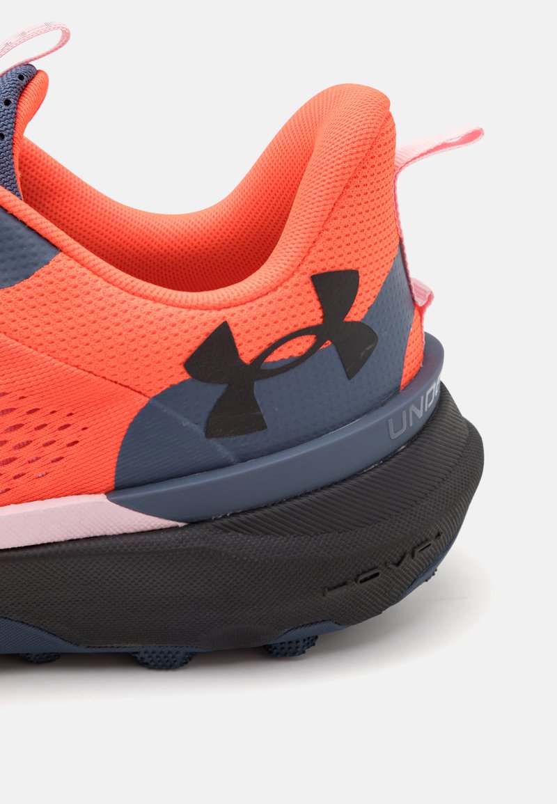 Zapatilla deportiva naranja con parte superior de malla, acentos en azul marino, suela negra y logo de Under Armour. Tacón redondeado y detalle de superficie texturizada.