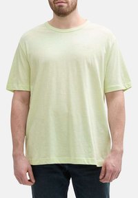 T-shirt vert clair à manches courtes en tissu doux, offrant une coupe décontractée, un col rond et un logo discret sur la poitrine.