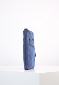 Tmavě modrá kožená taška s elegantním obdélníkovým tvarem, vybavená dvěma kapsami na zip na přední straně a malou logovou nášivkou.