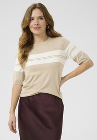 Top de punto beige de manga corta con rayas horizontales blancas, combinado con una falda burdeos. Textura suave y ajuste relajado.