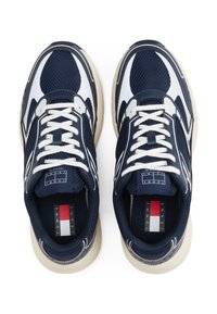 Granatowe siateczkowe sneakersy z białymi akcentami, masywną kremową podeszwą i kontrastującymi sznurówkami. Zawierają metkę z logo na języku i boku.