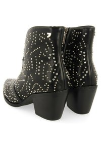 Botas de cuero negro hasta el tobillo con una superficie texturizada, adornadas con tachuelas plateadas en patrones decorativos, que cuentan con un tacón grueso y cierre de cremallera.