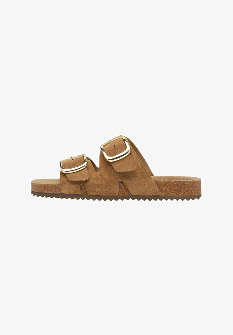 Bruine suede slipper met twee verstelbare gouden gespen en een kurken zool met een gematteerde rubberen onderkant.