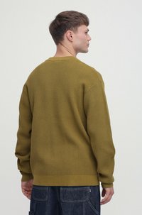 Oliwkowa, teksturowana dzianinowa sweter z długimi rękawami i okrągłym dekoltem, charakteryzująca się luźnym krojem i ściągaczem u dołu.