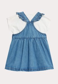 Denim ärmelloses Kleid mit einem weißen T-Shirt-Oberteil, das über Rüschenträger, einen gerafften Rock und ausgefranste Saumdetails verfügt.
