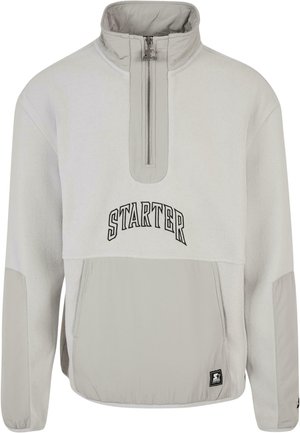 Šviesiai pilkas pūkuotas džemperis su pusiau užtrauktuku ir aukštu apykaklė. Yra juodas „STARTER“ tekstas ir viena priekinė kišenė su elastingu apačiu.