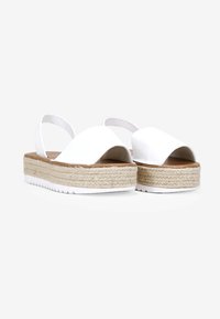 Sandalias de esparto blancas con diseño de punta abierta, parte superior de lona y suela de plataforma de yute trenzado. Correa ajustable en el talón para un mejor ajuste.