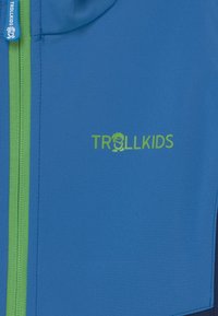Mėlynas vaikų užtrauktuku užsegamas džemperis, pagamintas iš lygios medžiagos, su žaliu užtrauktuku ir žaliu "TROLLKIDS" logotipu, kuriame pavaizduota personažo dizainas.