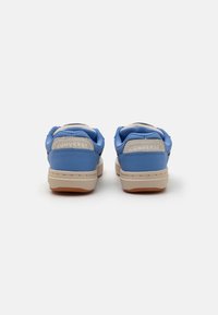 Adidași albaștri cu un superior din piele și textile, accente bej și branding "Converse" pe călcâi. Talpă plată din cauciuc cu un model texturat.