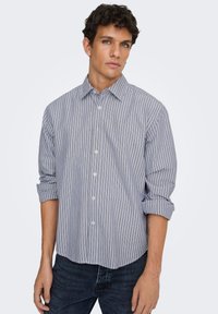 Ριγέ πουκάμισο με κουμπιά σε ανοιχτό μπλε και λευκό, με άνετη εφαρμογή, μανίκια που έχουν τυλιχτεί και απαλό βαμβακερό ύφασμα.