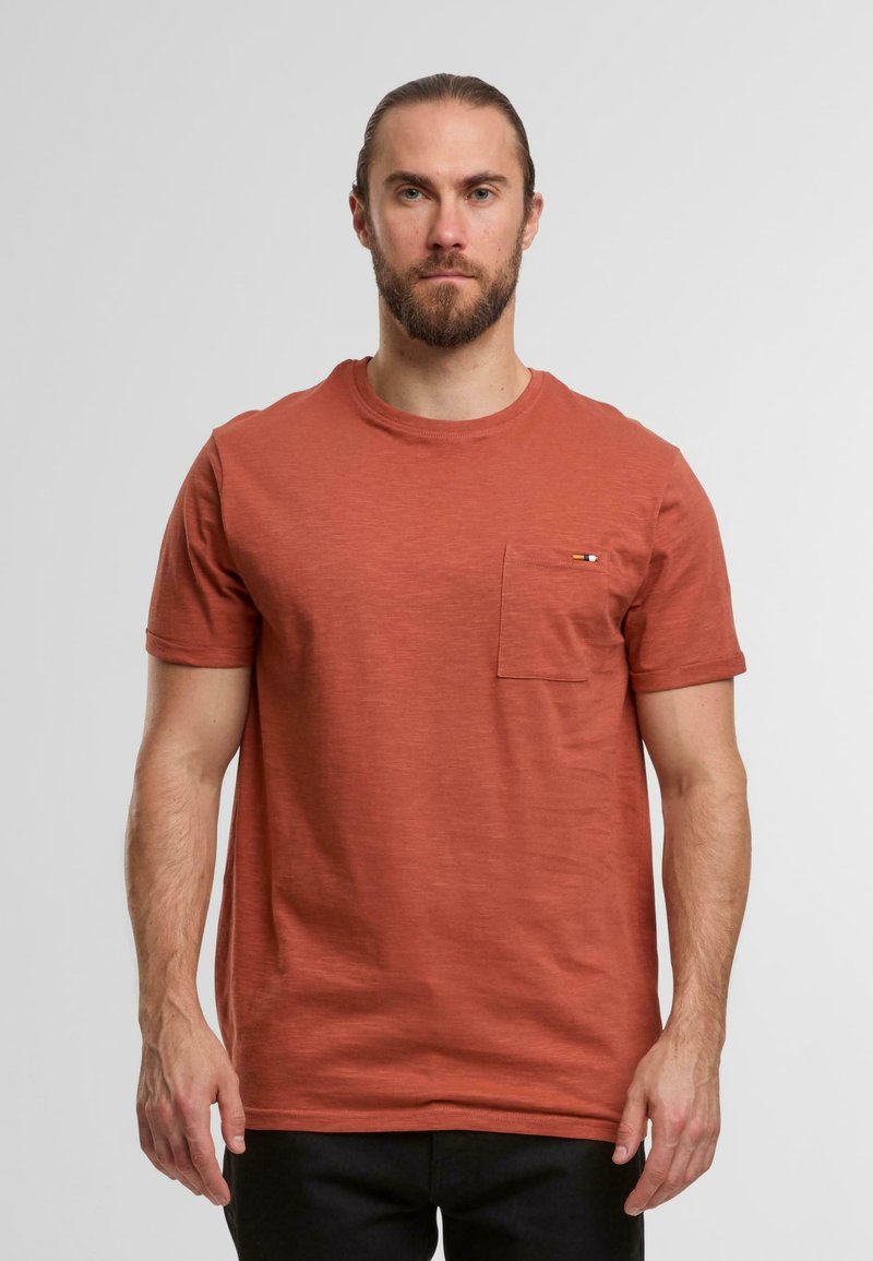 Rdzawoczerwony t-shirt z krótkim rękawem wykonany z miękkiego, teksturowanego materiału, z kieszenią na piersi i subtelnym akcentem logo.