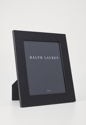 Cadre photo en cuir noir avec un design épuré, doté d'un avant transparent pour une photo de 20 cm x 25 cm et d'un support arrière surélevé.