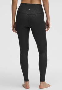Zwarte leggings met een subtiel luipaardprintpatroon, hoge tailleband en een gladde textuur, ontworpen voor comfort en flexibiliteit.