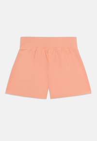 Persikofärgade shorts gjorda av mjukt material, med ett texturerat högelastiskt midjeband och en löst sittande design.