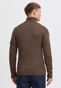Maglione marrone lavorato a maglia con colletto alto, polsini e orlo a costine, tessuto testurizzato con silhouette aderente, visto da dietro.