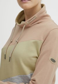 Felpa con cappuccio nei colori rosa, verde e grigio. Caratterizzata da un alto collo con lacci regolabili e una patch con logo sulla manica. Tessuto morbido.