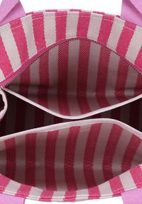 Interno della borsa tote a righe in rosa e crema. Materiale in tela con due scomparti divisi da una cerniera. Foderato con un motivo a spina di pesce.
