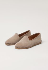 Beige suede espadrilles with a closed toe, stitched jute midsole, and a smooth leather lining. Features a decorative trim along the edge.