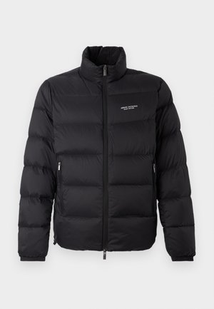 Giubbotto imbottito nero con colletto alto, dotato di una zip frontale e due tasche laterali. Tessuto leggermente trapuntato con logo del marchio sul petto.