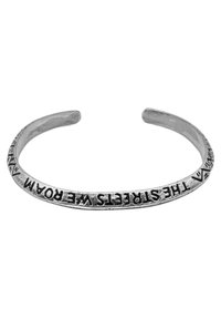 Silver cuffarmband med en öppen design, prydd med ingraverad text längs bandet och en slät, polerad yta.