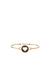 Pulsera de metal dorado con un charm circular en blanco y negro que presenta un corte en forma de corazón y letras alrededor del borde. Diseño suave y minimalista.