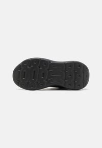 Semelle de sneaker, en caoutchouc noir avec une surface texturée, présentant des motifs moulés et une forme arrondie. Talon renforcé pour plus de durabilité.