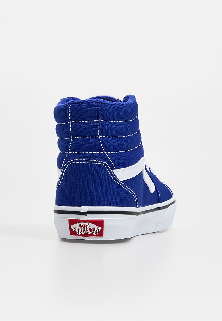 Zapatilla alta de lona azul real, con costuras blancas y un logo lateral, tejido texturizado y una suela de goma negra y blanca.