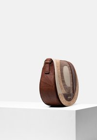 Borsa a spalla in pelle marrone con un design curvo e multi-texturizzato che presenta accenti in beige e sabbia. Mostra un dettaglio con finestra trasparente.