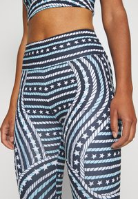 Leggings sportivi con uno sfondo blu navy e motivi di corda e stelle blu. Realizzati in materiale elastico, con una cintura alta.