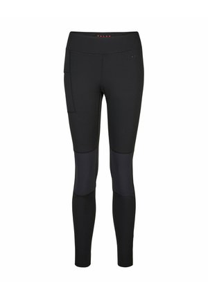Main glissant dans la poche latérale d'un legging de sport noir ajusté avec des détails de couture visibles.