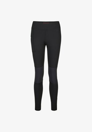 Hand, die in die Seitentasche von schwarzen, eng anliegenden Sportleggings mit sichtbaren Nahtdetails gleitet.