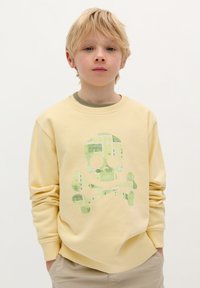 Gele sweatshirt met lange mouwen, voorzien van een groen schedel en kruisbotten graphic. Zachte stof, relaxte pasvorm en geribbelde halslijn.