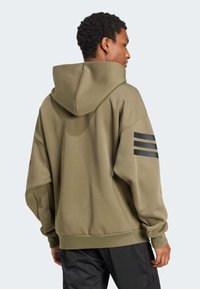 Felpa verde oliva con cappuccio, presenta accenti neri a tre strisce sulle maniche, realizzata in materiale liscio e offre una vestibilità comoda.