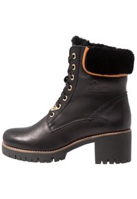 Stivale alla caviglia in pelle nera con tacco spesso, collo foderato in pelliccia, occhielli dorati e lacci neri. Suola con tasselli per una maggiore aderenza.