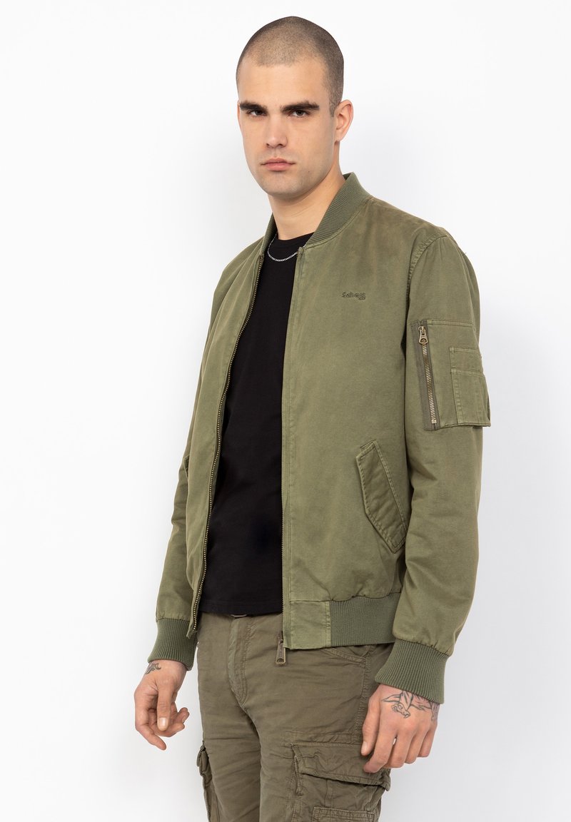 Chaqueta bomber verde olivo con cremallera frontal, puños acanalados y un bolsillo con cremallera en el brazo izquierdo; tejido de mezcla de algodón.