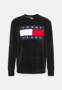 Pull noir en maille avec un logo rectangulaire en bleu marine, rouge et blanc. Encolure ras du cou et ourlet côtelés avec une finition texturée.