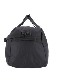 Černá látková taška s kulatým tvarem, nastavitelným ramenním popruhem a horními rukojeťmi. Obsahuje přezkový uzávěr a texturovaný povrch.
