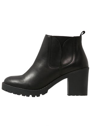 Zwarte leren enkelboot met een ronde neus, blokhak, elastische zijpanelen en een rubberen zool met profiel. Gladde textuur met een kleine glans.