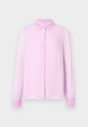 Jasnoróżowa bluzka z teksturowanym, kwiatowym kołnierzem, długimi przezroczystymi rękawami i falbanami przy mankietach. Zapięcie na guziki z przodu.